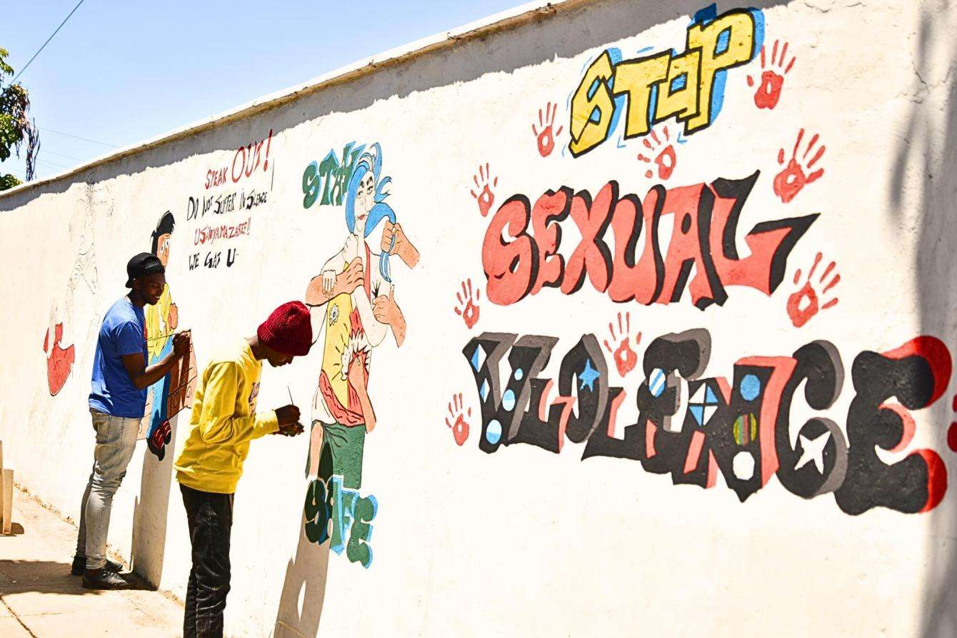Staff in front of a sexual violence awareness mural in Nairobi. 