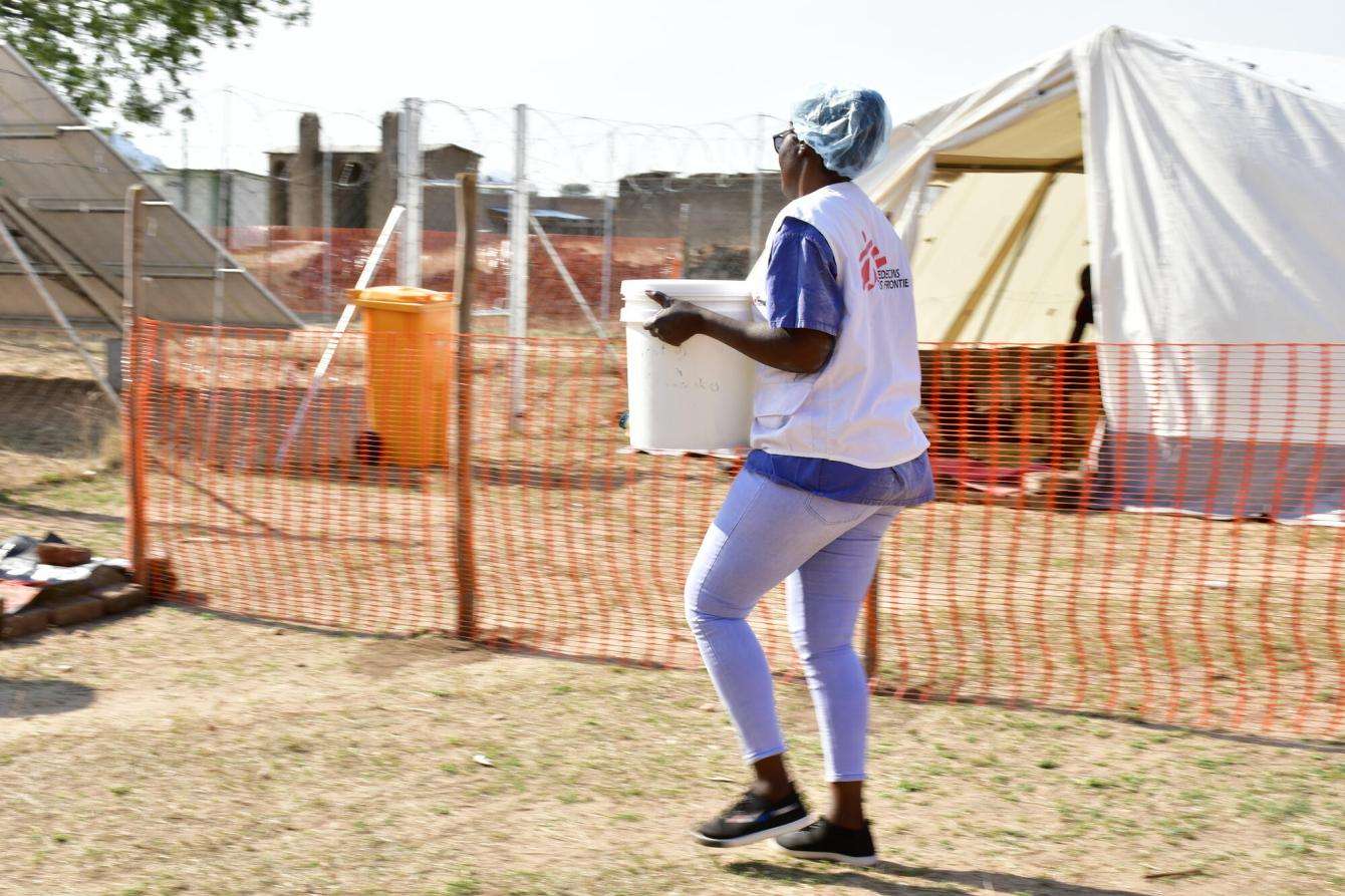 MSF nurse carries a bucket of oral rehydration solution to the cholera treatment unit in Zimbabwe.