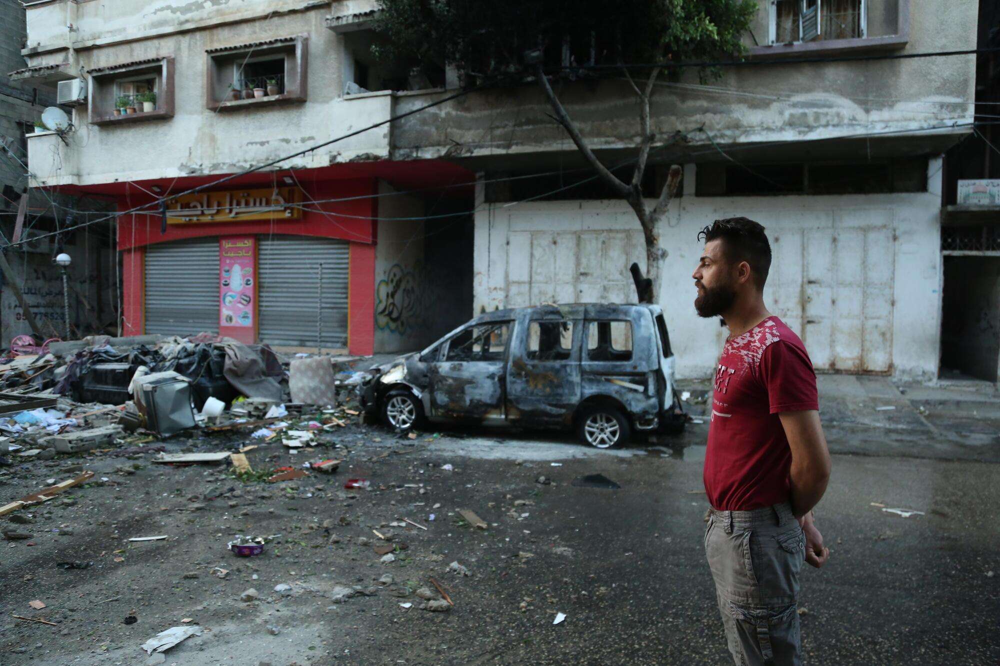 A Palestinian man stands in front of wreckage in Gaza City, Palestine. 