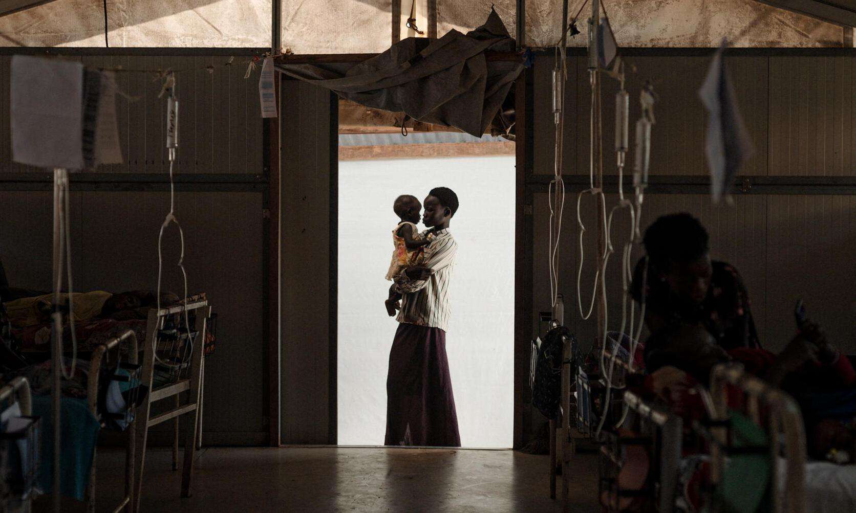 Silhouette of a mother holding a child in the door frame of an MSF hospital in South Sudan.