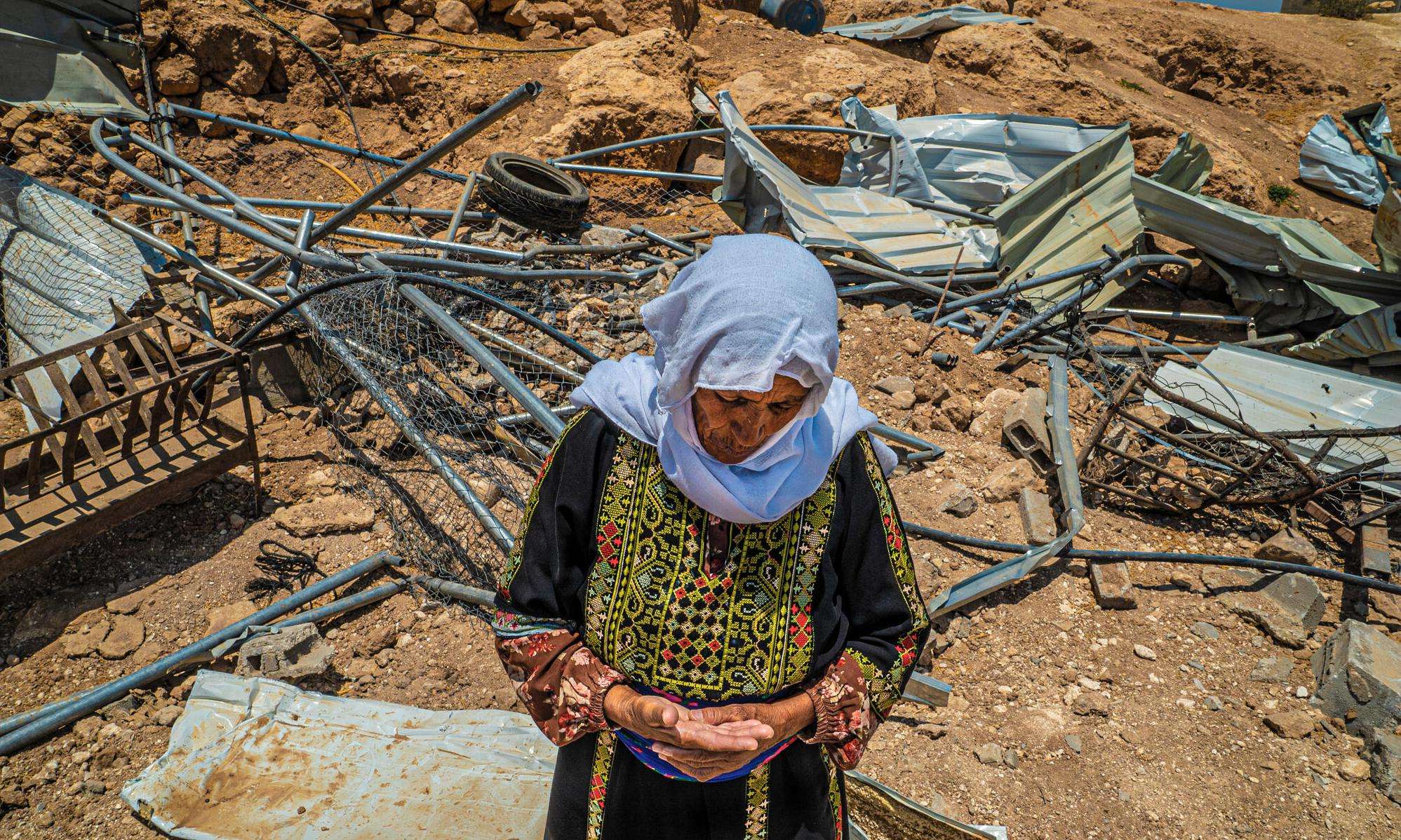 A woman in traditional Palestinian dress in front of the ruins of her home after it was demolished by Israeli forces in Masafer Yatta, West Bank.