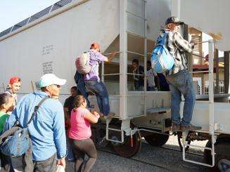 Men, women, and children board the moving train to reach the northern border of Mexico.