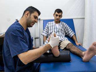 MSF physiotherapy manager Shadi Al-Najjar treats a patient at Al Awda hospital in Gaza in 2019