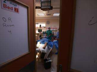 Open door to an operating room at Al Aqsa Hospital in Gaza, as doctors perform surgery on a patient.