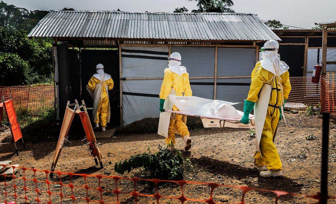MSF staff members carry a deceased Ebola patient to the morgue in Kailahun, Sierra Leone. 