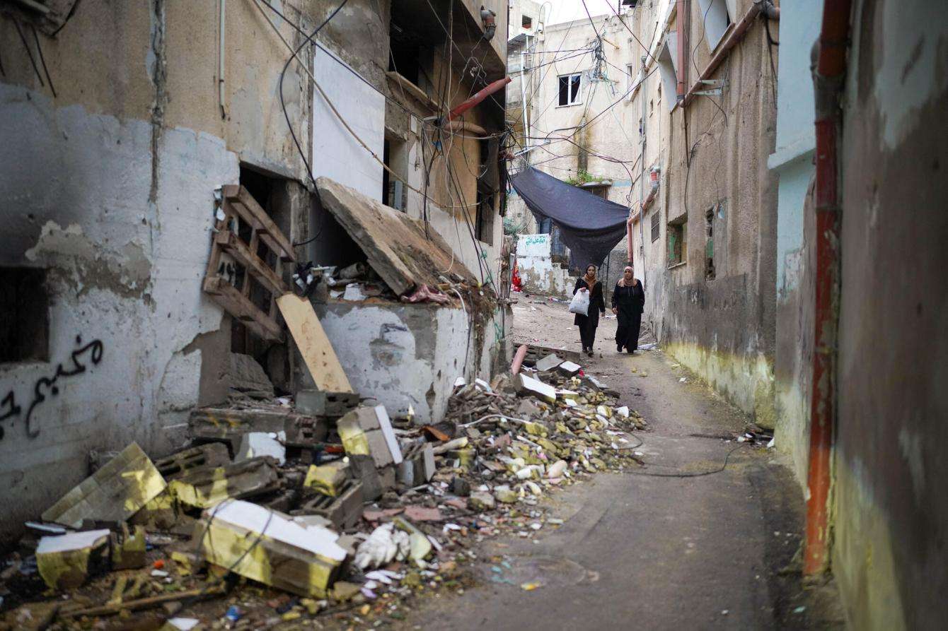Two Palestinian women walk through an alleyway strewn with rubble in Jenin refugee camp, West Bank, after an Israeli attack.