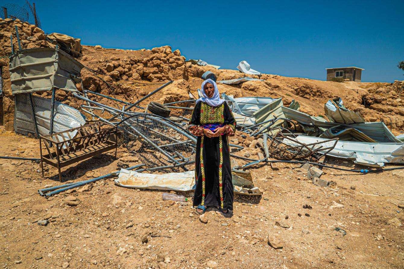 A woman stands before the rubble left of her home after it was demolished by Israeli forces in Masafer Yatta, West Bank.