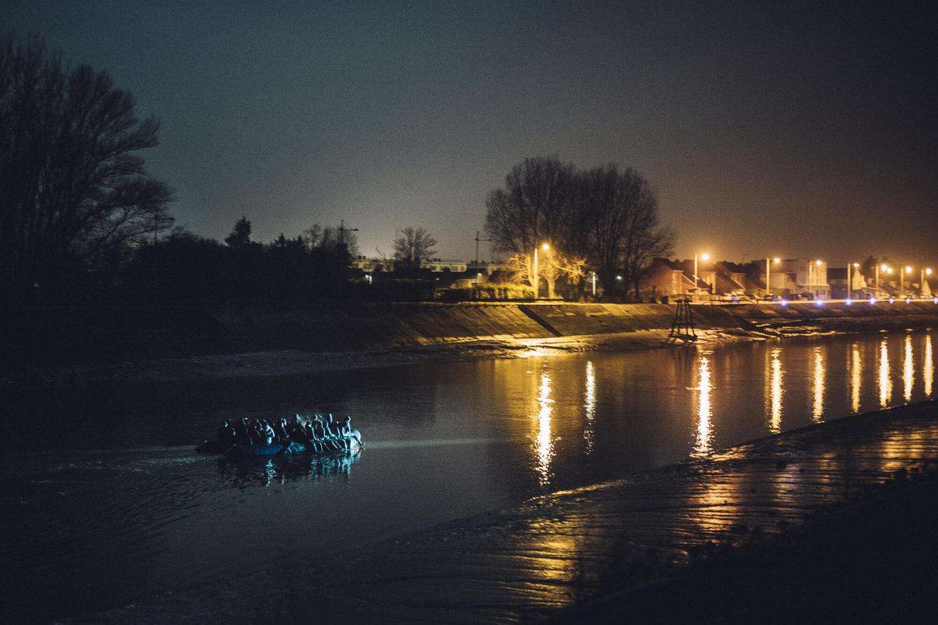 A rubber boat sets off from the French coast for England at night.