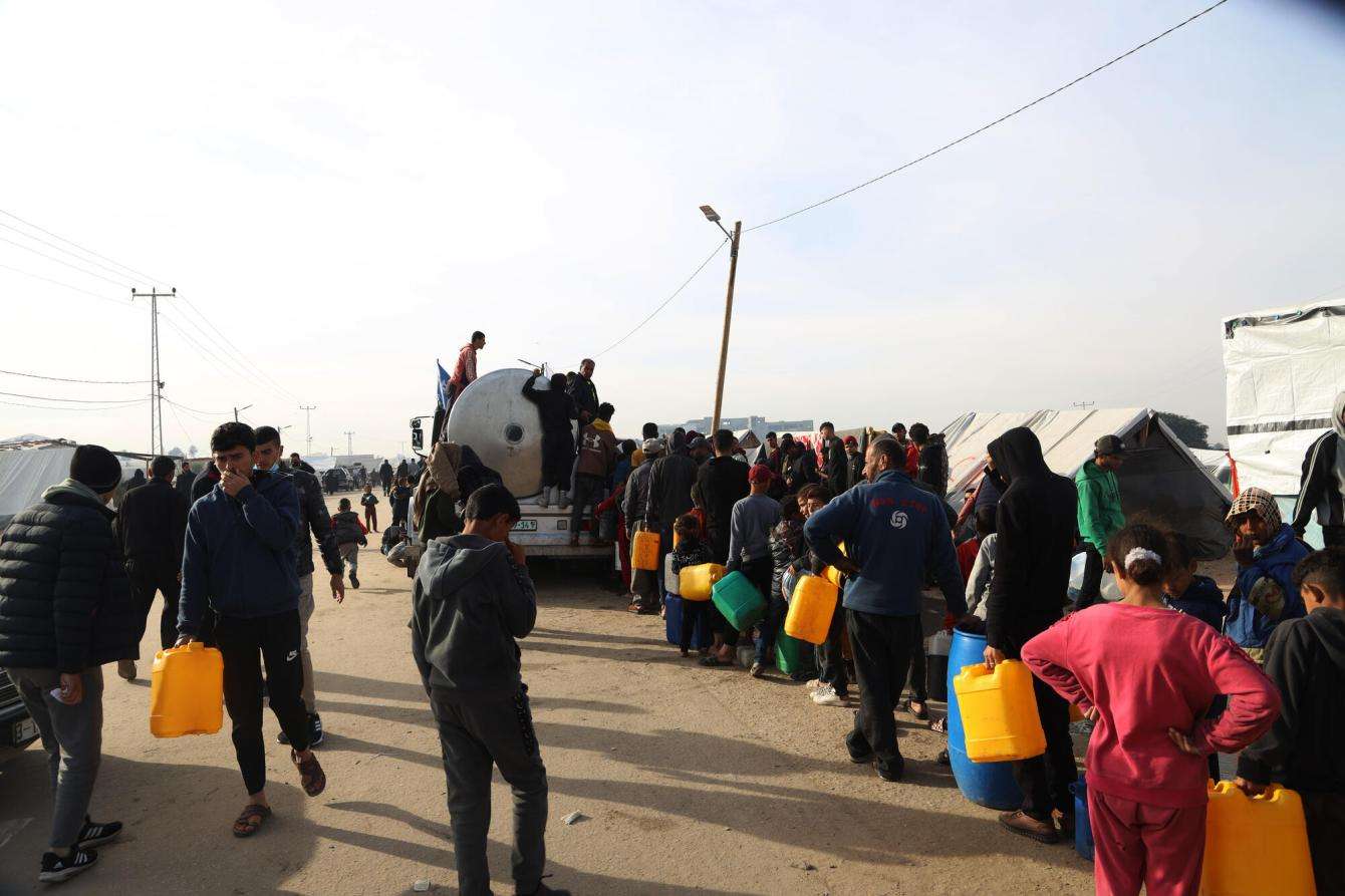 Displaced Palestinians wait in line to get safe drinking water in the Tal Al-Sultan area of the southern Gaza town of Rafah.
