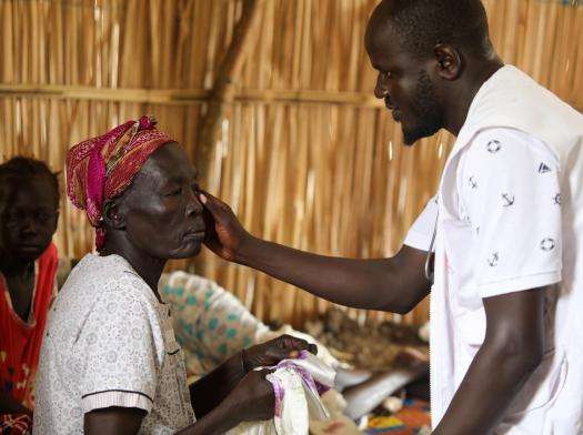 A man who works for MSF examines a patient at MSF'S mobile clinic in Renk.