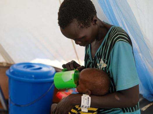 A mother feeds her child at MSF's inpatient therapeutic feeding center in Renk.