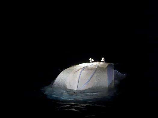 A capsized boat in the Central Mediterranean Sea at night.