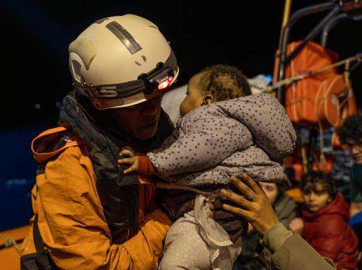 An MSF search and rescue team member rescues a child from a boat in distress in the Central Mediterranean Sea.