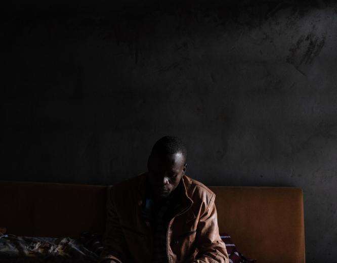 A man sitting and looking down in a dark room in Libya.