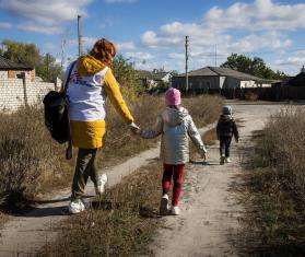 MSF psychologist and children walk outside in Ukraine.