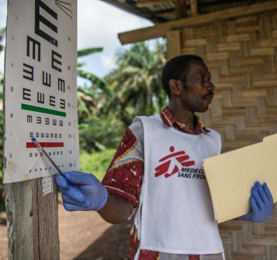 An MSF outreach worker performs a vision test with an Ebola survivor in Mabekoh, Sierra Leone.