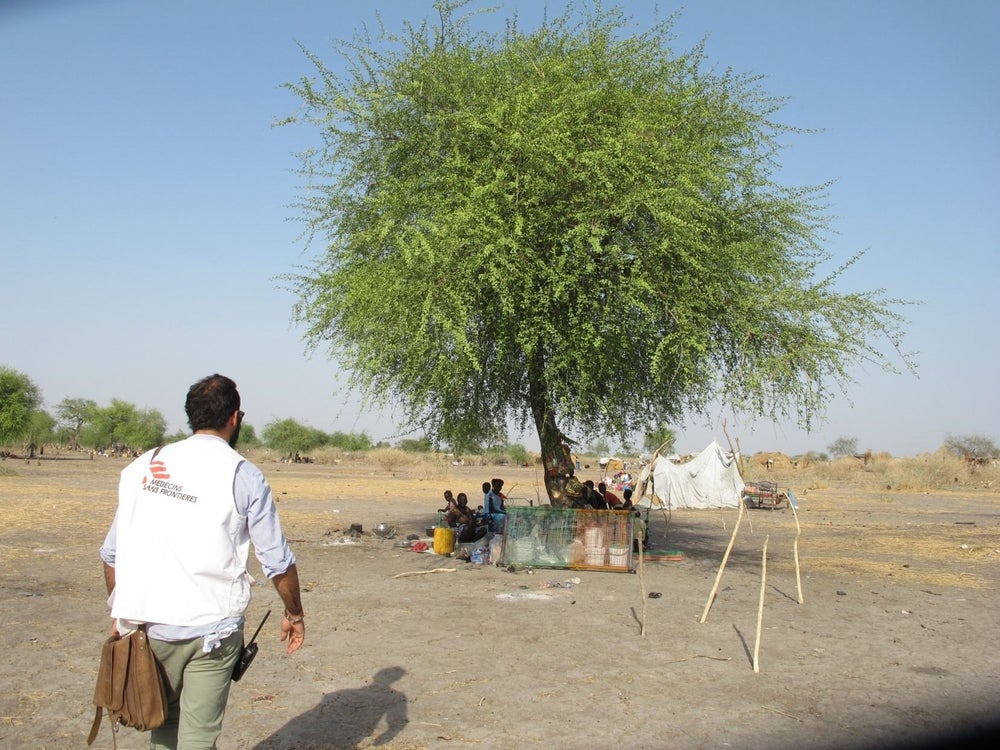 A MSF staffer visits a family living under a tree in Noon.