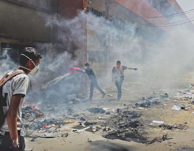 Palestinians walk through smoke in the streets of Gaza.
