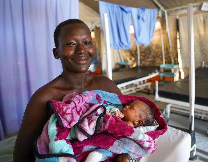 A mother smiles holding her baby in Kajo Keji, South Sudan