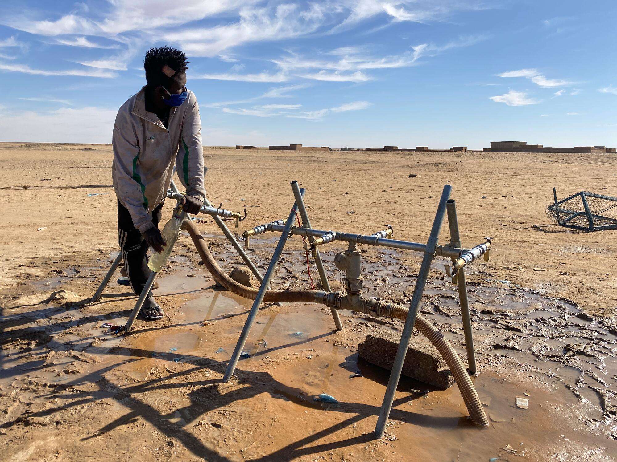 A young man fills a water bottle from a pump installed by MSF, in Assamaka. Niger, November 2020.