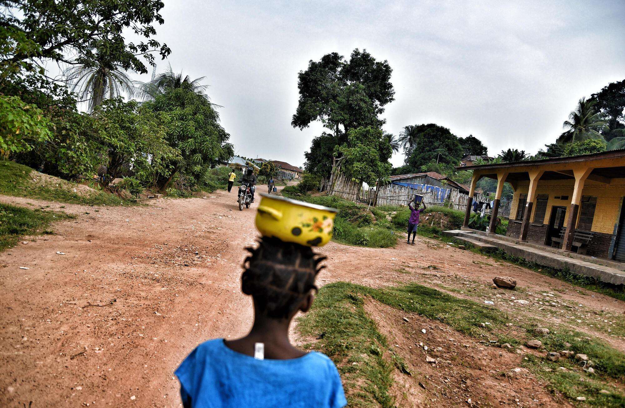 A young girl carries food as she walks through one of the villages in Gorama Mende.