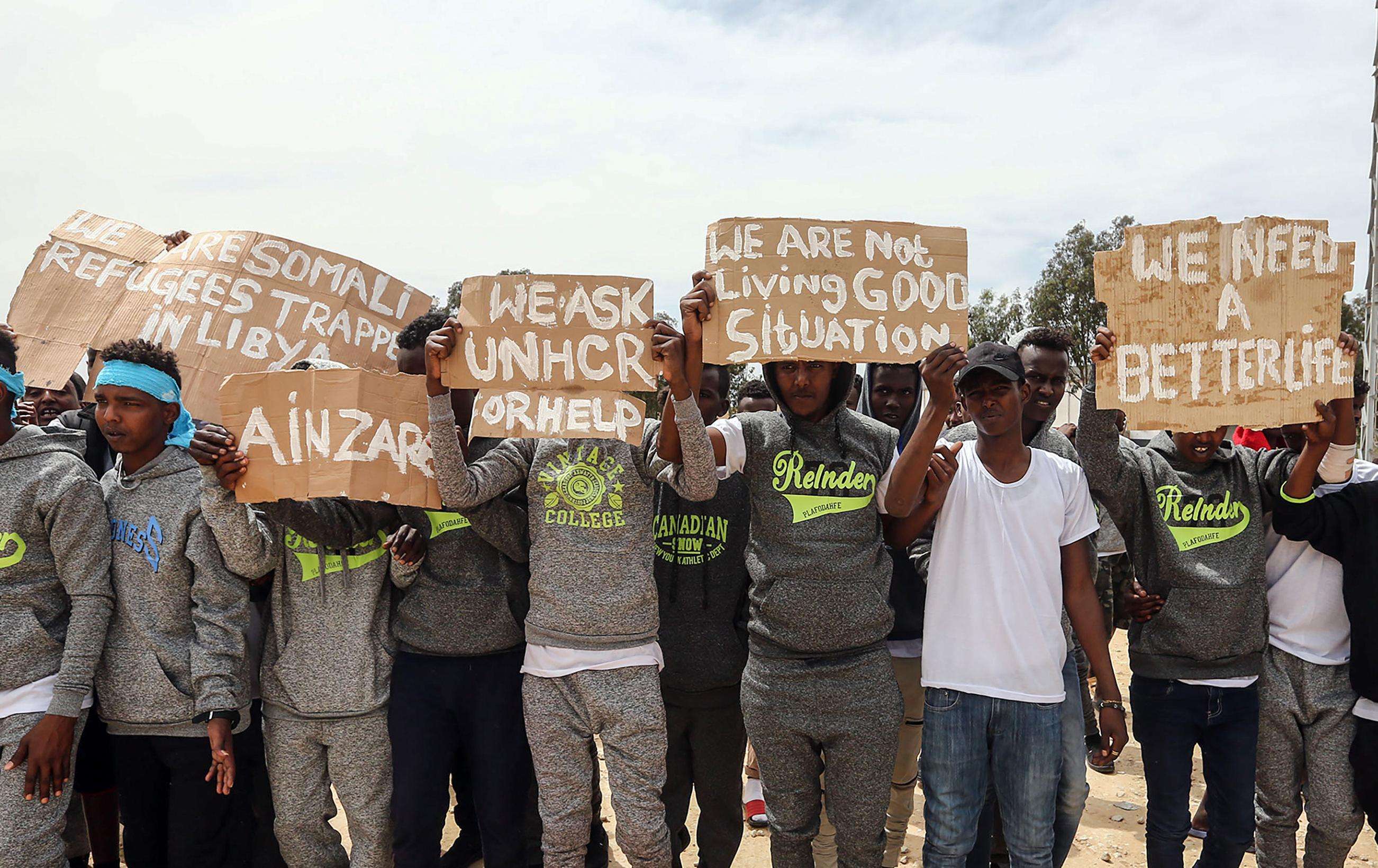 Migrants hold placards during United Nations Secretary-General Antonio Guterres (not pictured) visit to Ain Zara detention centre for migrants in the Libyan capital Tripoli on April 4, 2019.