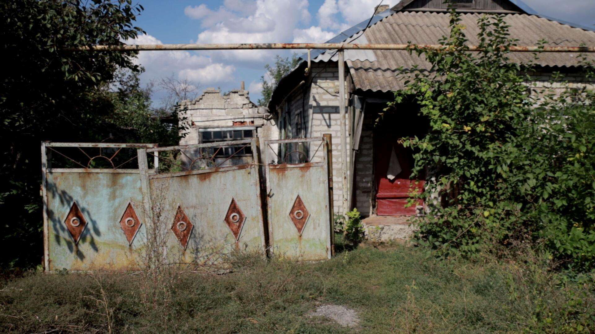 A dilapidated house with tin roof and broken gate