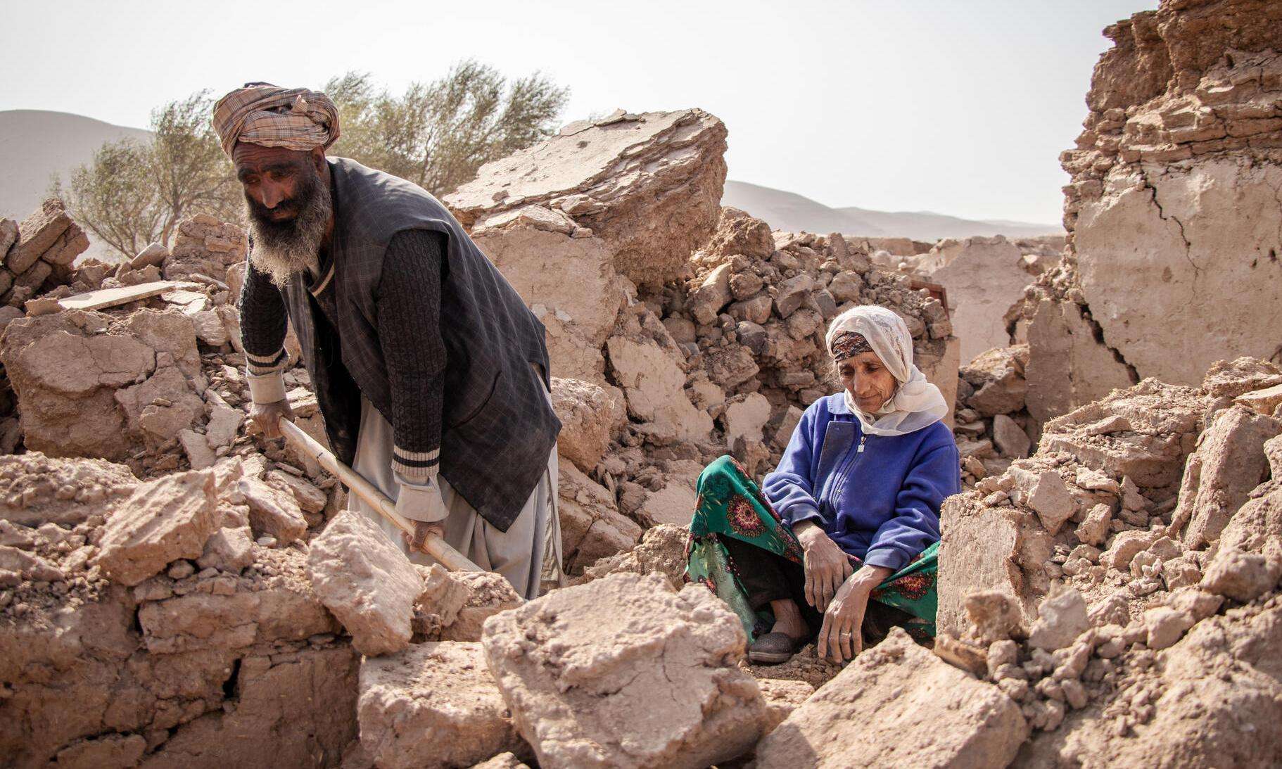 An Afghan man digs through the remains of his house beside his mother after the earthquake in Herat, Afghanistan. 