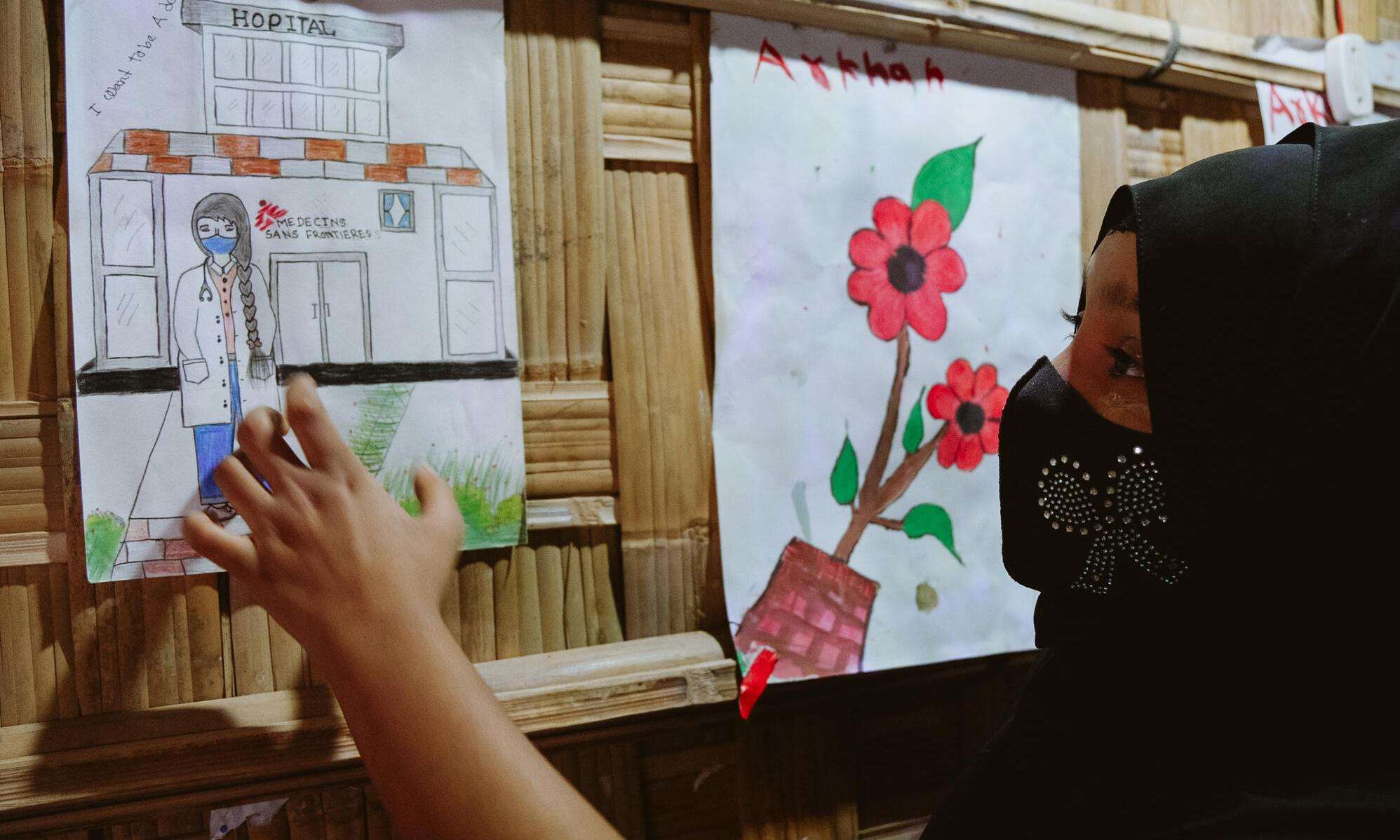 A young Rohingya refugee points to a picture she drew of an MSF doctor in a clinic.
