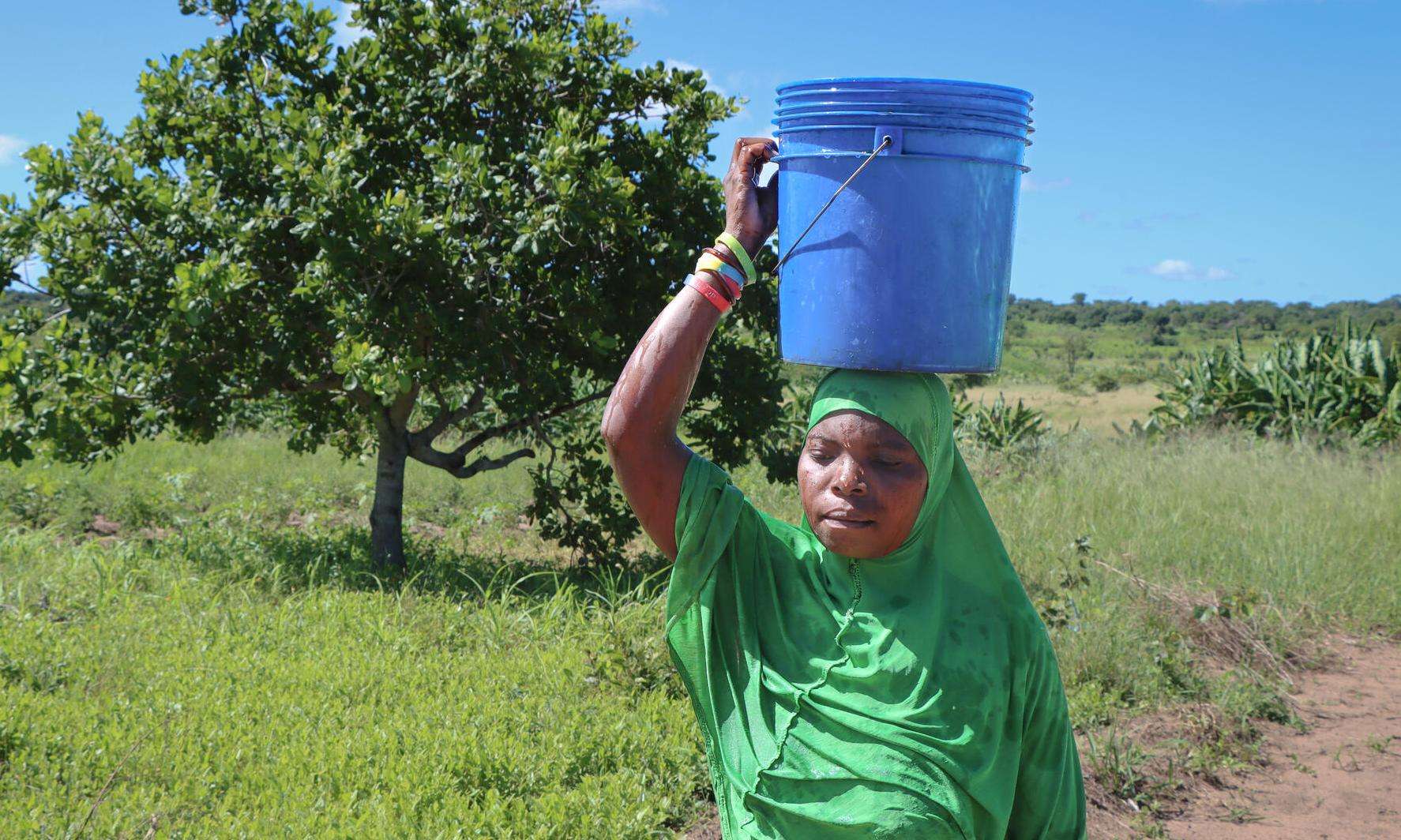 A woman carrying a bucket of water on her head in Mozambique