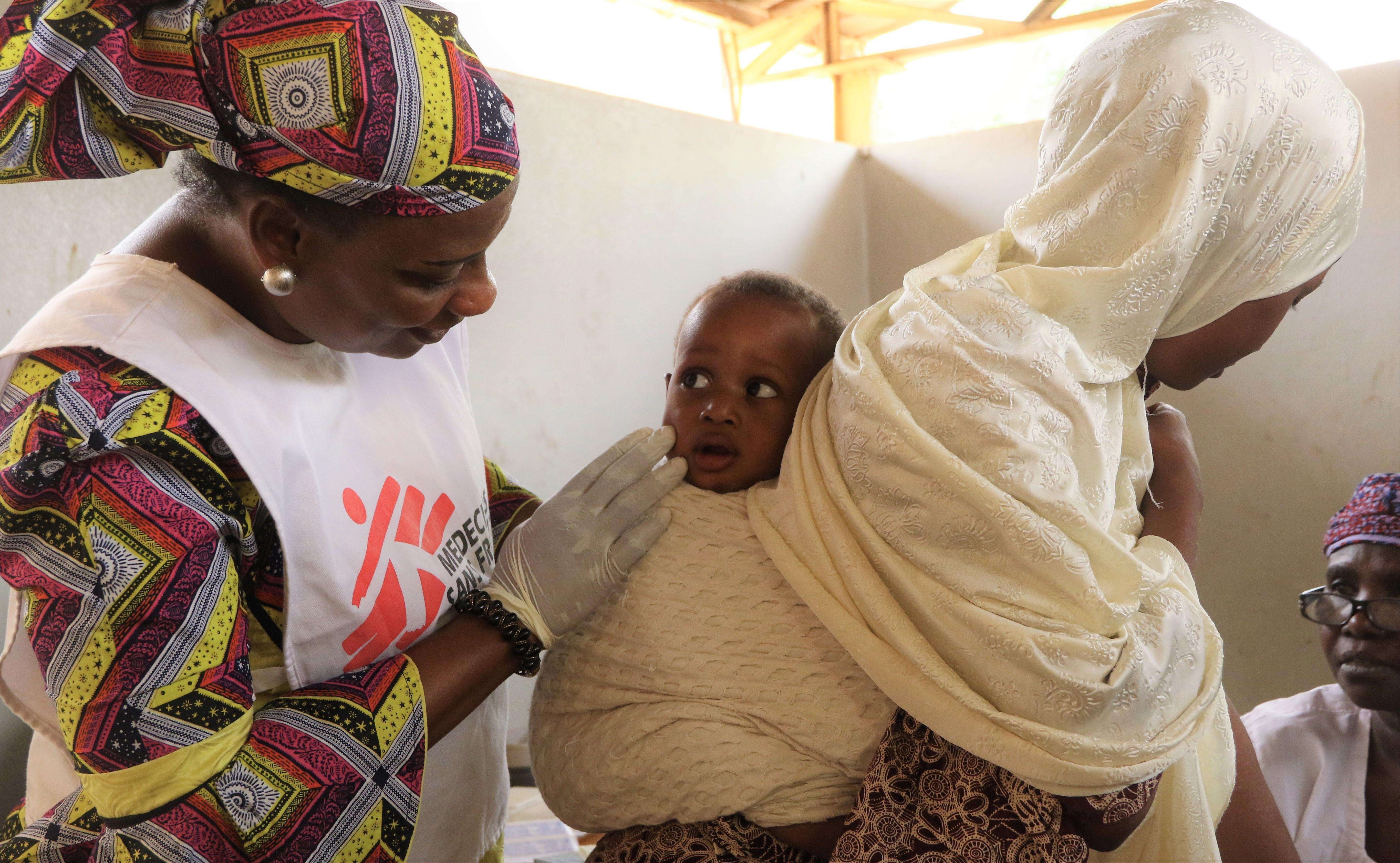 MSF field worker interacting with a mother and her son seeking treatment at a health center administering the Meningitis vaccination campaign in Niamey region.