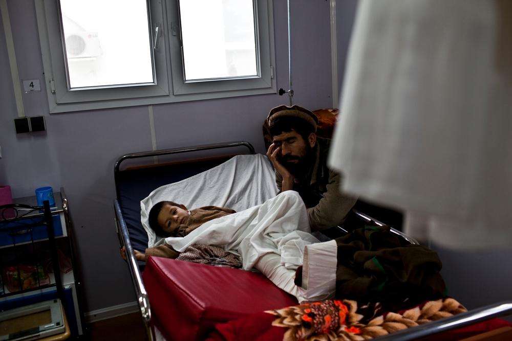A man naps next to his son recovering in the MSF trauma hospital in Kunduz, northern Afghanistan, November 30, 2011