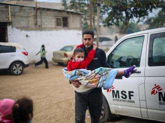 A Palestinian man carries an injured child to MSF's clinic at Rafah Indonesian Hospital in Gaza.