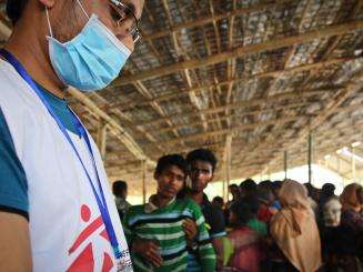 A staff worker greets new arrivals at an MSF mobile clinic, where they are provided with health check-ups, general healthcare, and nutritional screening.