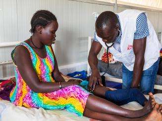 A woman on a bed is being examined by a doctor in the MSF hospital in Agok