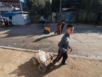 Displaced Palestinian children carry water back to their tents in the southern Gaza town of Rafah’s Al-Shaboura neighborhood.