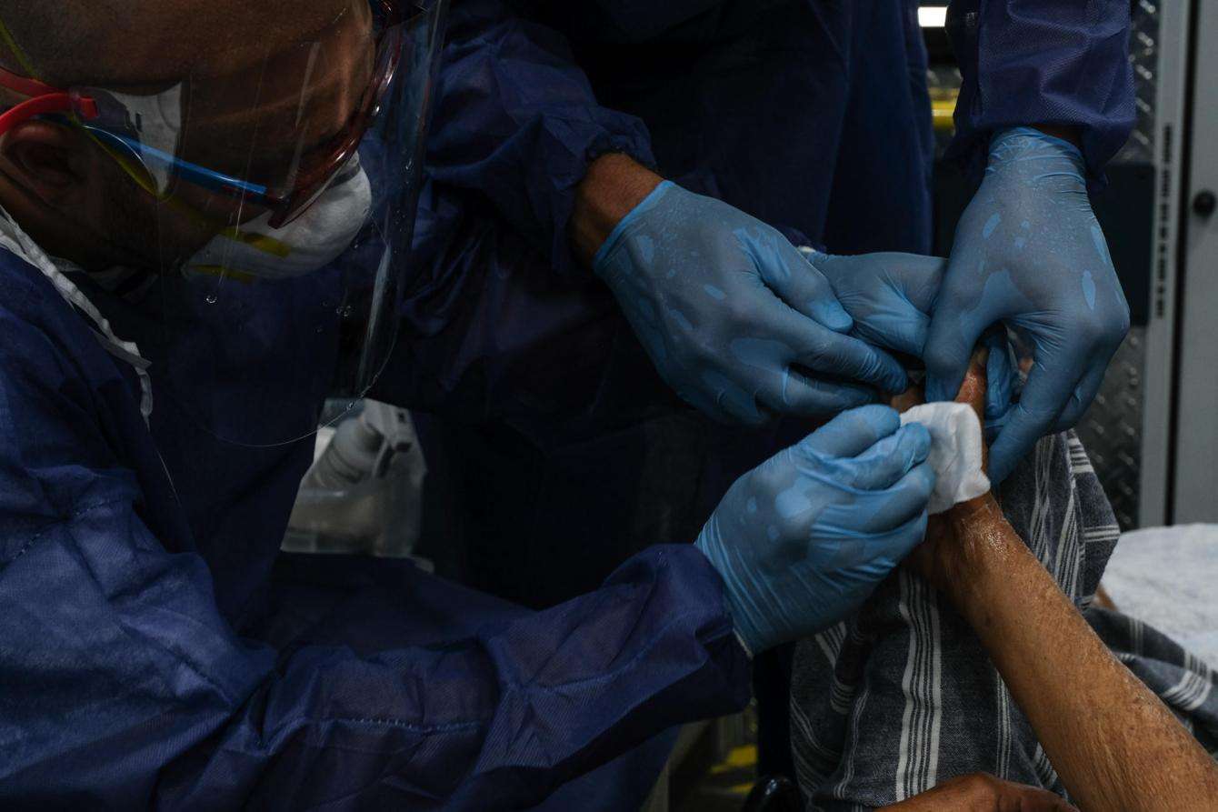 Doctors Without Borders/Médecins Sans Frontières (MSF) physician Dr. Jonathan Caldera (left) and MSF nurse Rolando Betancourt (right) clean the wounds on a patient’s foot during a medical consultation in Arecibo, Puerto Rico.