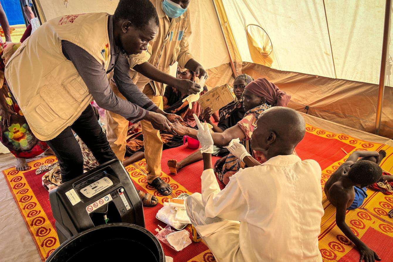 An MSF aid worker provides medical care to Sudanese refugee in tent hospital in Chad