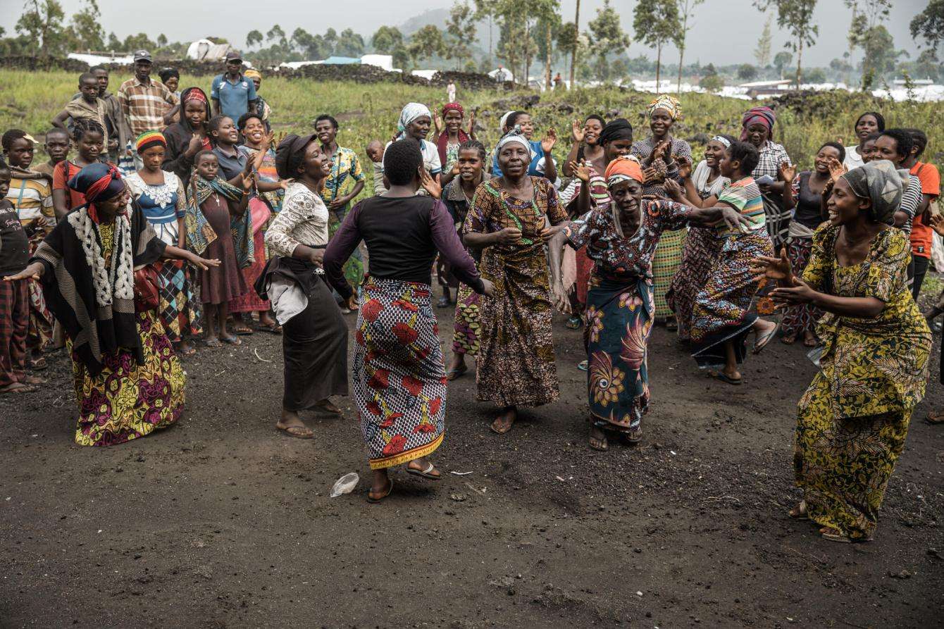A group of women dancing outside in beautiful patterned dresses. 