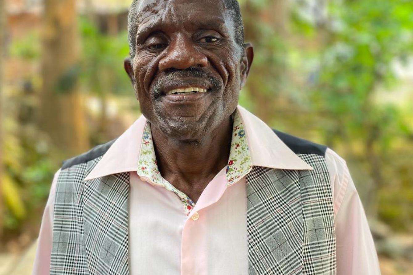 An older man standing outside and smiling at the camera.