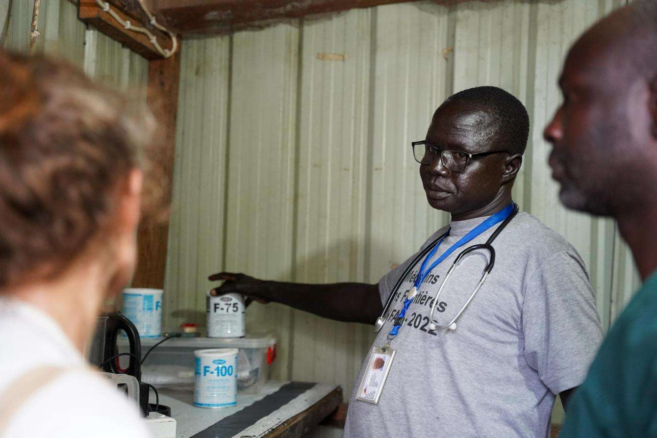 An MSF doctor in a pediatric ward of the MSF hospital in Old Fangak, Jonglei state speaks to two others while pointing to a can of formula milk.
