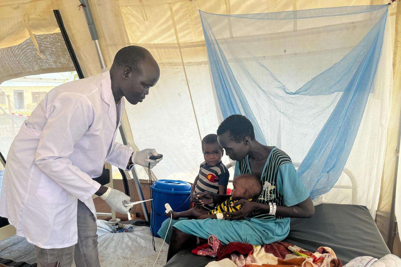 An MSF nurse inside a plastic MSF tent treating a child being held by a mother in  in the Renk Civil Hospital, Upper Nile state. 