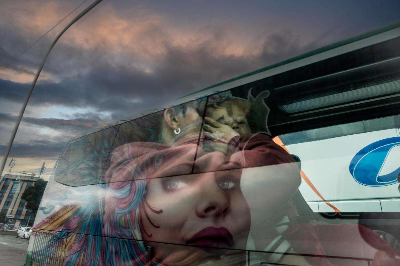 The side of a bus painted with a woman's face under a cloudy sky