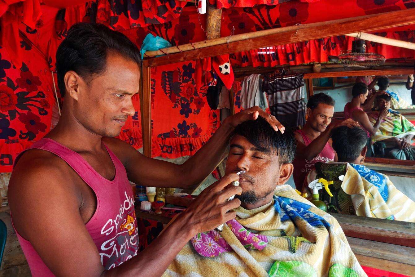 A Rohingya man trims the beard of another Rohingya man in Cox's Bazar.