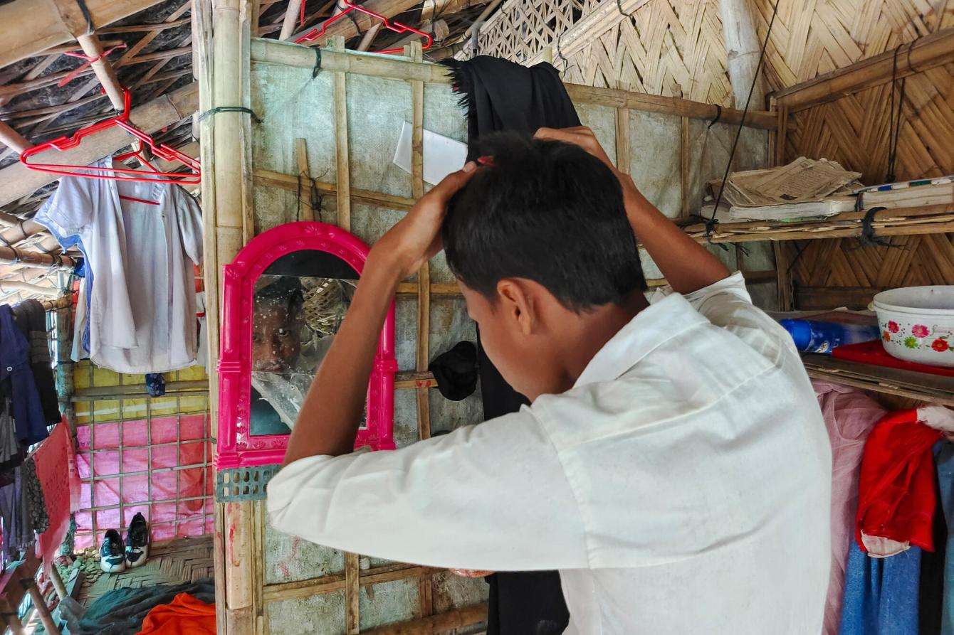 A young Rohingya man combs his hair in a mirror in Cox's Bazar, Bangladesh.