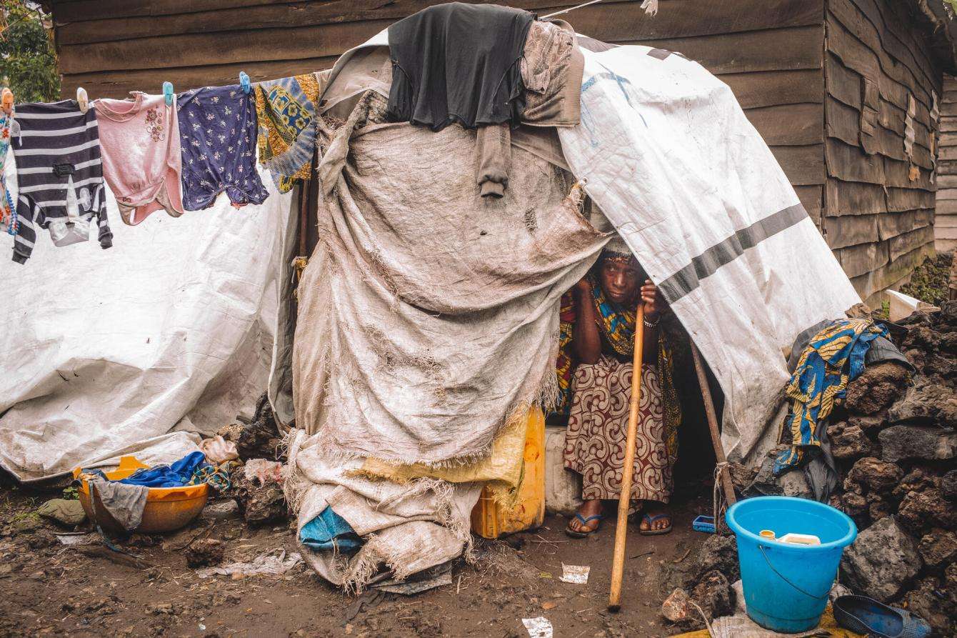 Jeanne peers out of her makeshift shelter in Kanyaruchinya camp for displaced people in DR Congo.