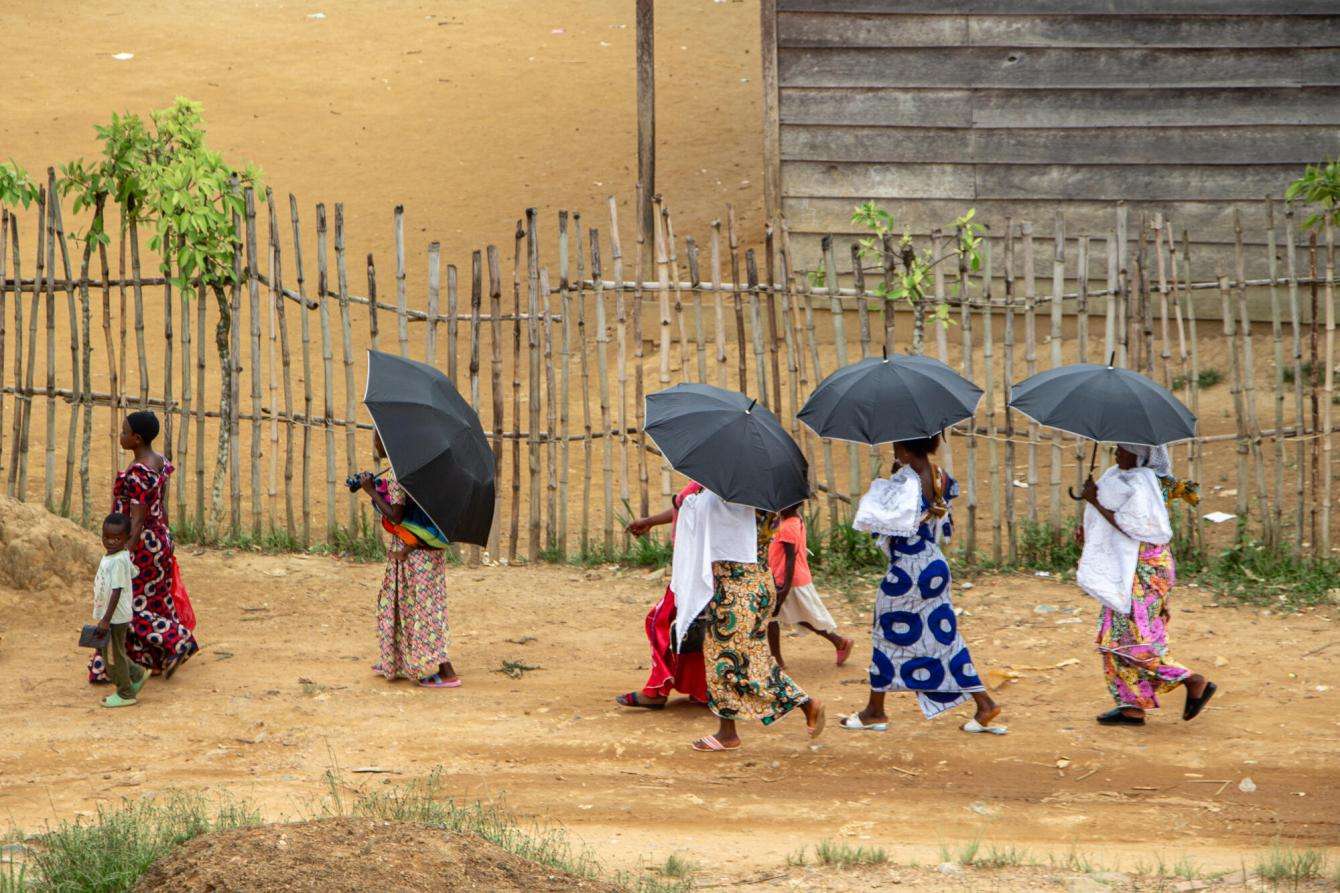 Women walking with umbrellas outside a village in North Kivu. 