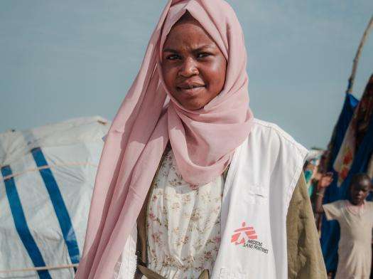 An MSF staff member in a white vest and pink hijab at Camp Ecole in Chad.