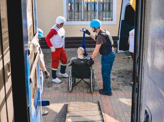 MSF teams assist an elderly patient in a wheelchair as they evacuate Kherson, Ukraine.