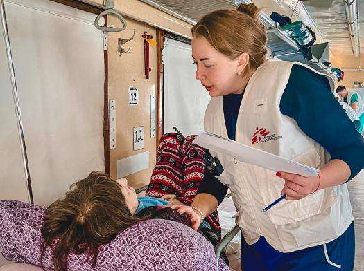 An MSF doctor aboard the medical evacuation train in Ukraine checks on a young patient.